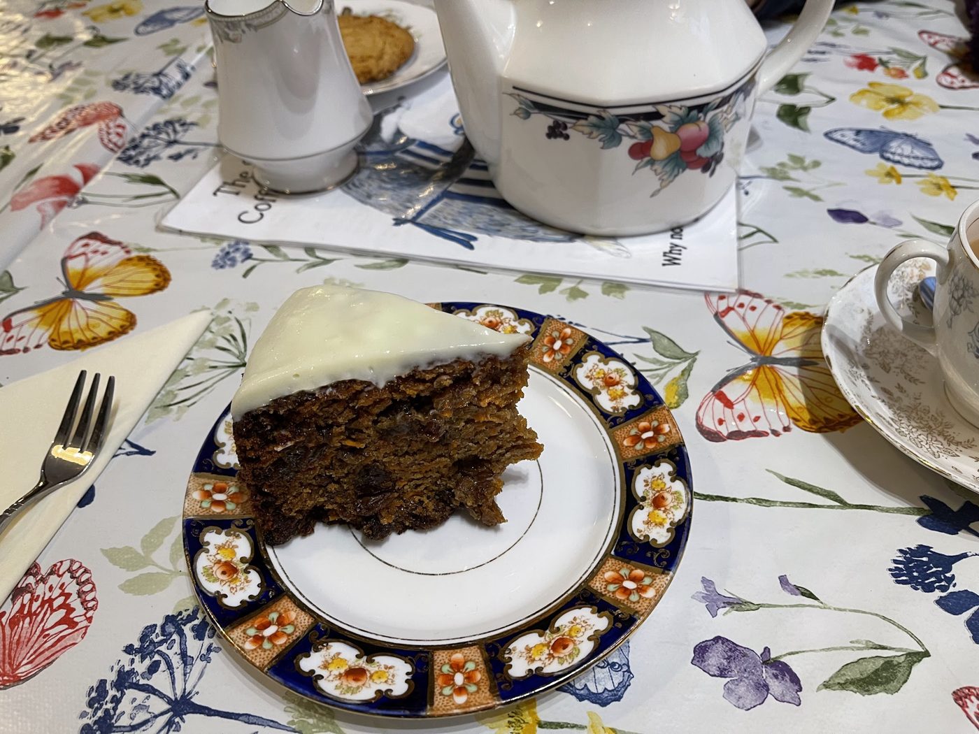 A slice of dark cake with icing on a patterned plate