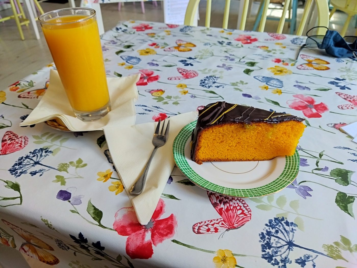 A slice of orange cake with a glass of orange juice